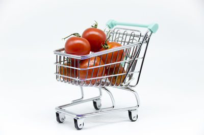 Close-up of tomatoes with basket on white background