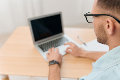 Midsection of man using laptop on table