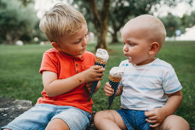 Baby and toddler sharing some ice cream looking at each other