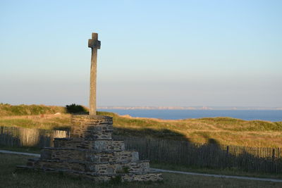 Stone cross on land against sky