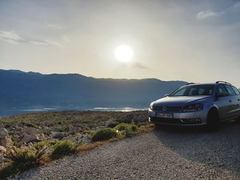 Car on sea by mountains against sky