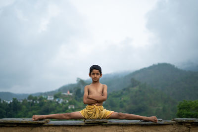 A young indian cute kid doing yoga in the mountains,wearing a dhoti