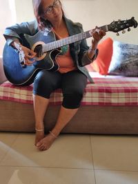 Full length of man playing guitar at home