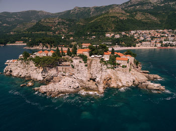 High angle view of townscape by sea against mountain