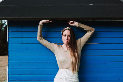 Full length of young woman standing against blue wall