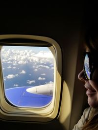 Close-up of man looking through airplane window