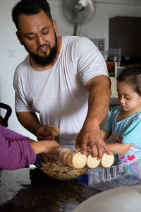 Father giving food to daughter at home