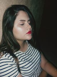 Young woman with eyes closed relaxing against wall in darkroom