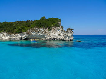 Scenic view of sea and rock formation against blue sky