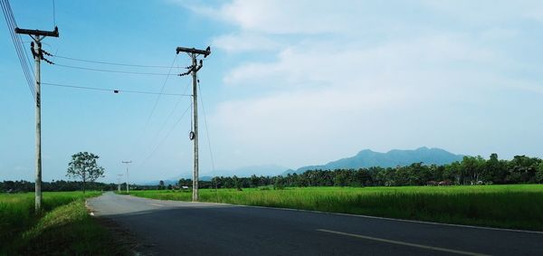 Road by field against sky