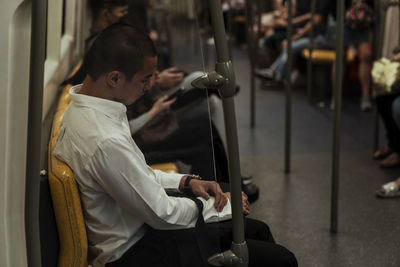 Side view of man sitting on seat in train