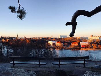 Buildings by river against clear sky at sunset