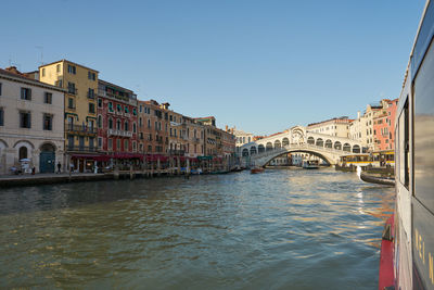 Arch bridge over river amidst buildings in city against sky rialto venice canal grande