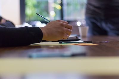 Cropped hand of businessman with pen and paper on table