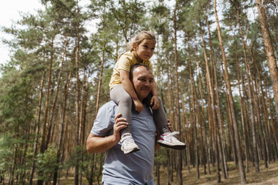 Mature man carrying girl on shoulders in forest