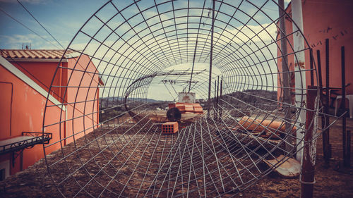 Man seen through chainlink fence against sky