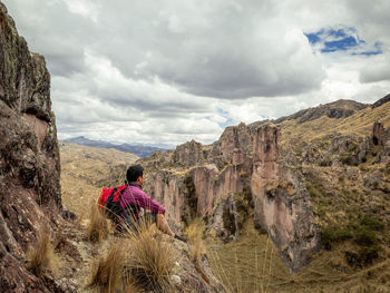 Rear view of man looking at mountains against sky