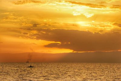 Scenic view of sea against cloudy sky during sunset