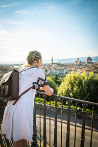 Rear view of woman standing by railing against sky