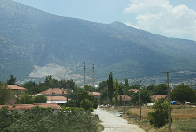 Street amidst buildings and mountains against sky