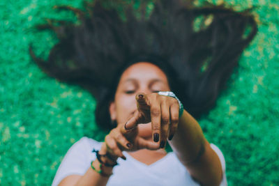 High angle view of young woman pointing while lying on field