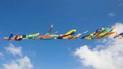 Low angle view of multi colored flags hanging against sky