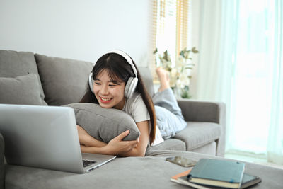 Young woman using mobile phone while sitting on sofa at home