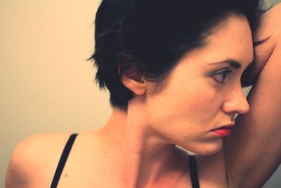 Close-up portrait of young woman against gray background