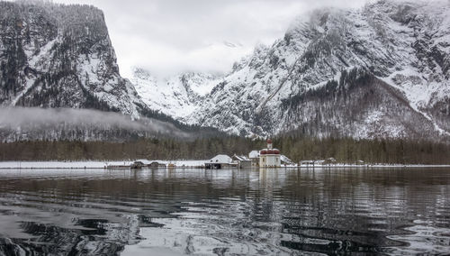 Scenic view of lake by snowcapped mountains against sky