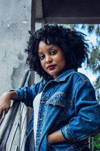 Portrait of young woman standing by railing