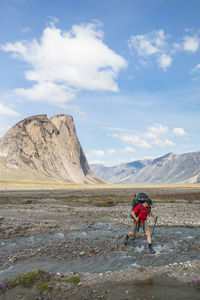 Hiker crosses river in akshayak pass.