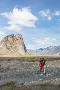 Hiker crosses river in akshayak pass.