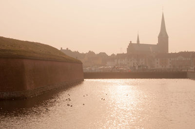 River with buildings in background at sunset