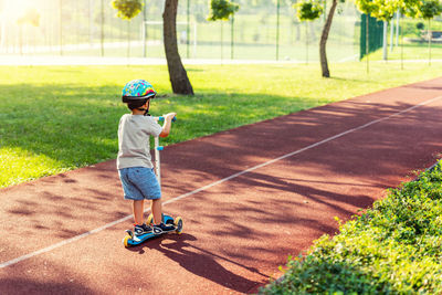 Rear view of boy with umbrella on grass