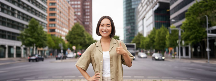 Portrait of young woman standing in city