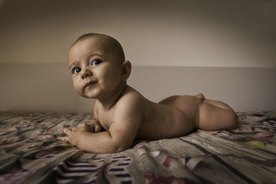 Portrait of shirtless baby boy on bed at home