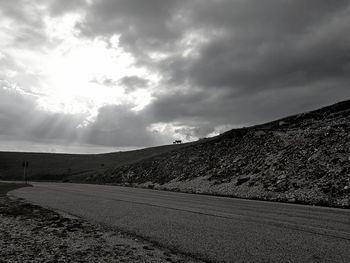 Empty road leading towards mountains against sky