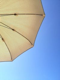 Low angle view of beach umbrella against clear blue sky