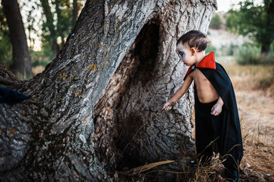 Full length of boy on tree trunk in forest