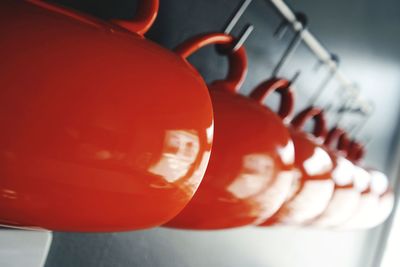 Close-up of orange mugs hanging