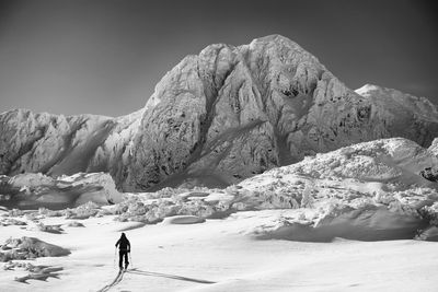 Man walking on snow covered mountain against sky