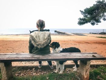 Rear view of woman with dog sitting on beach