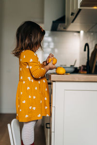 Midsection of woman with orange at home