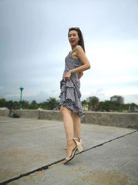 Full length portrait of woman standing against sky