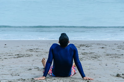 Rear view of man sitting on beach