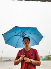 Man holding umbrella while standing on rainy day