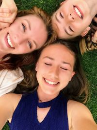 Portrait of a mother and her two daughters laying in the grass smiling