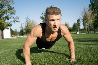 Portrait of young man exercising on field