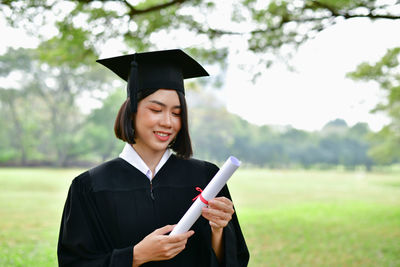 Smiling young woman holding camera in park