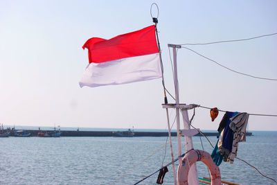 Sailboat with indonesian flag sailing on sea against sky